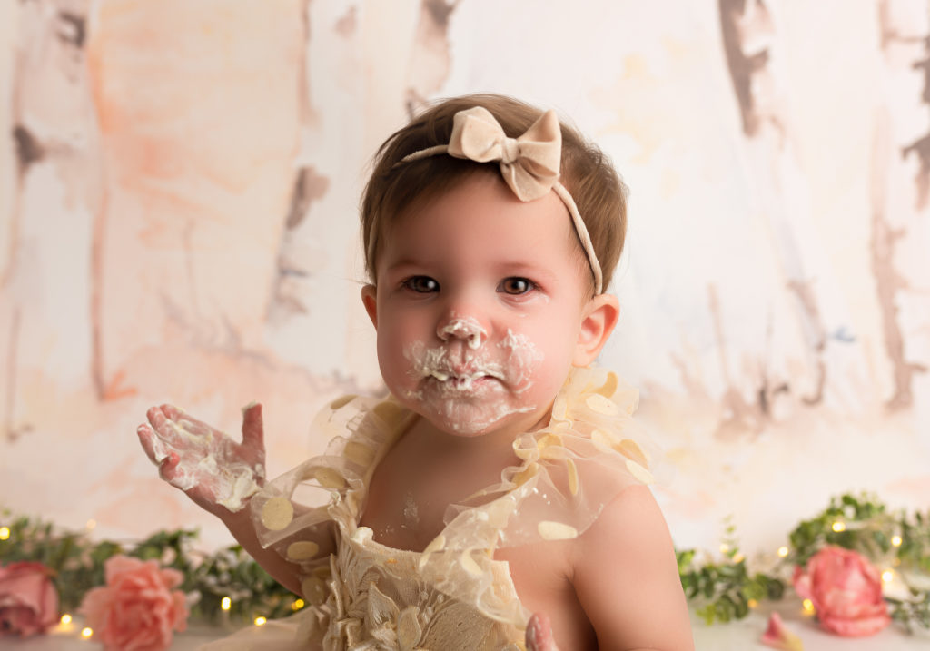 One year old girl with cake all over her face during her charlotte cake smash session
