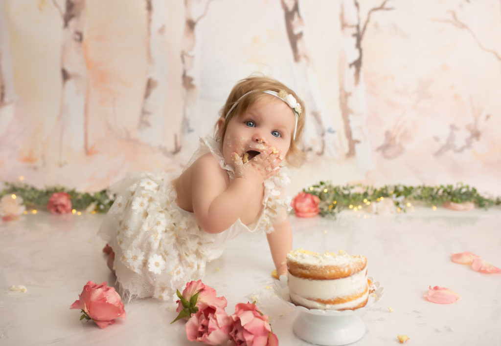 One year old girl crawling with eating cake at her cake smash session