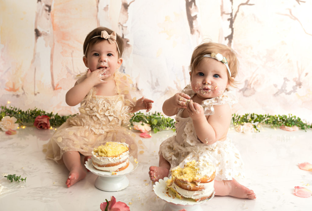 Twin girls eating cake together at their cake smash session in charlotte north carolina