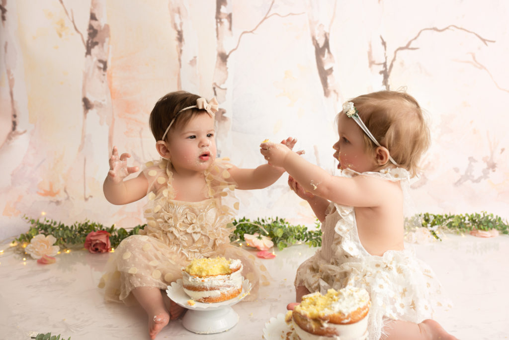 Twin girls sharing cake at their charlotte cake smash session