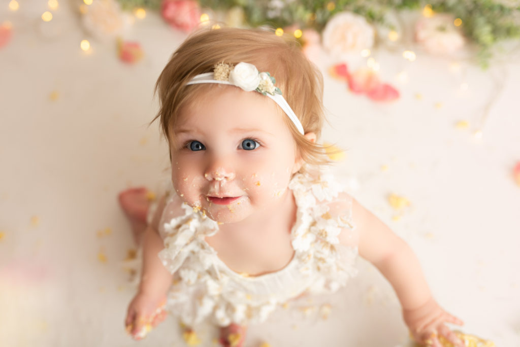 One year old girl looking into camera for a photo at a cake smash session