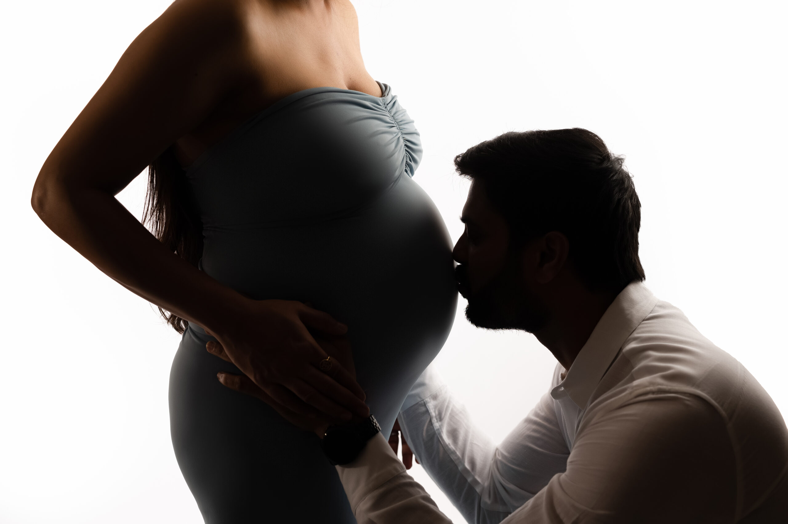 Father-to-be kissing the belly of mother-to-be during a maternity photoshoot