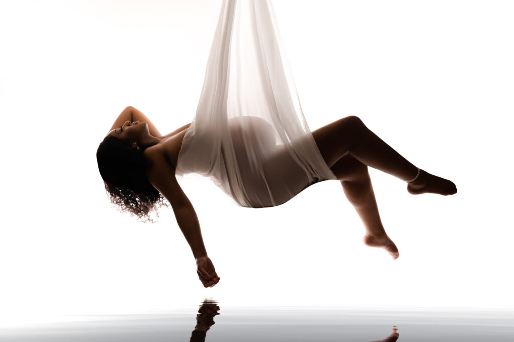 Photo of pregnant mother hanging from silk with her belly exposed showing off her body during her charlotte maternity session