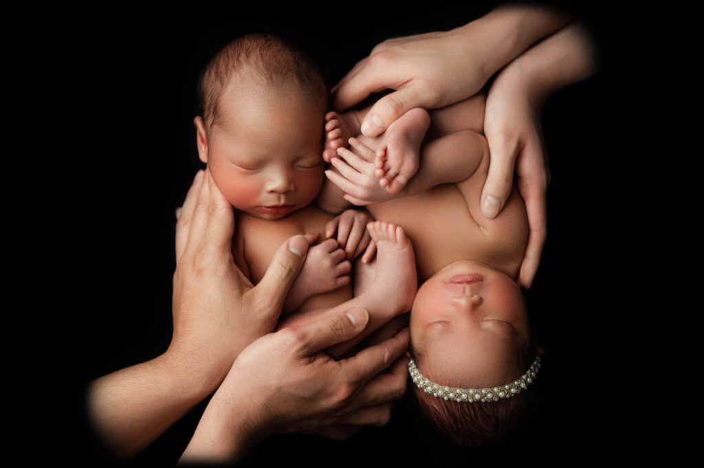 Professional photo of twin newborns cuddled up and being held by parents during their newborn photography session.