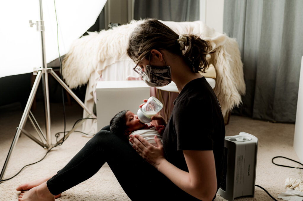 A charlotte newborn photographer feeding a baby with a bottle during their newborn session.