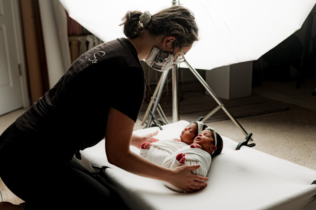 Newborn photographer snuggling twin girls closer together during their baby photography session.