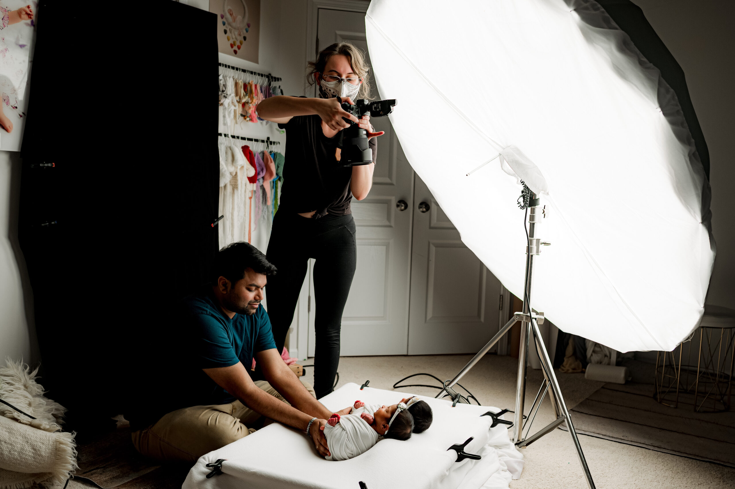 Photo of a photographer photographing twin baby girls and their dad's hands from above during their charlotte newborn photoshoot