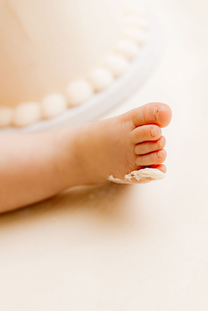 Close up detail of baby toes with birthday cake frosting during cake smash session